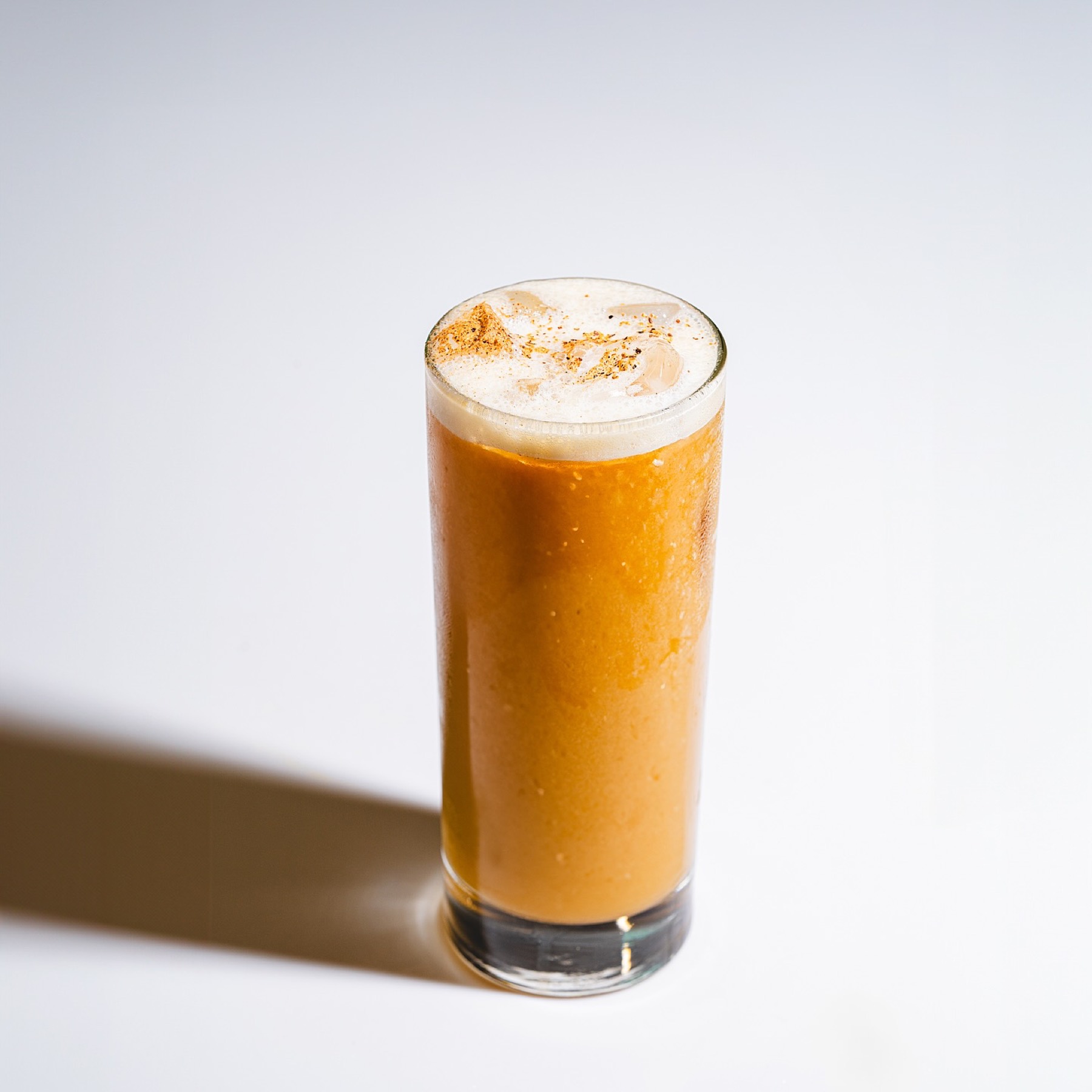 Miel de Octubre, bebida alta color naranja con espuma de nuez moscada